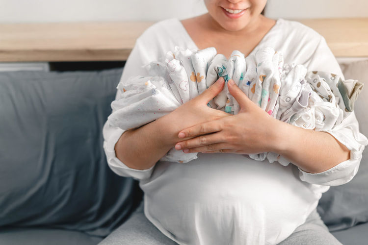 Midsection of woman holding baby while sitting at home