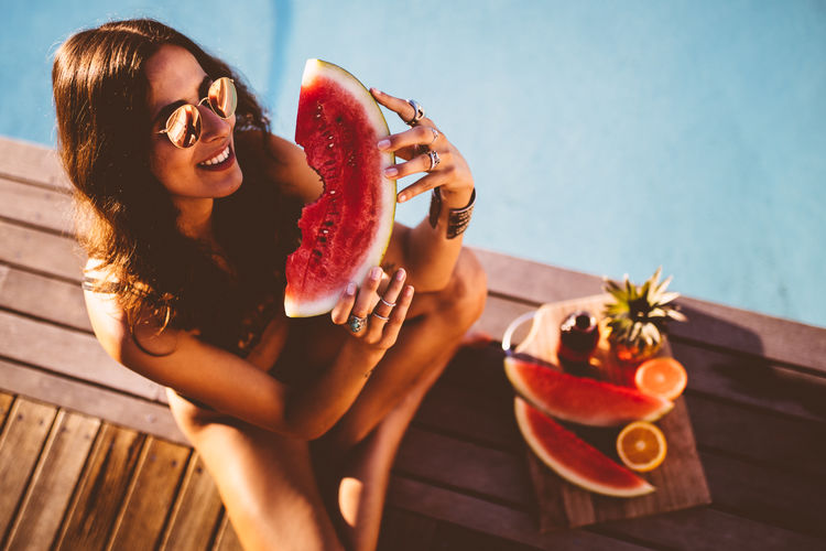 Woman eating fruit by swimming pool