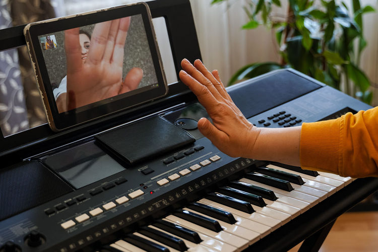 Midsection of woman gesturing while video conferencing over digital tablet at home