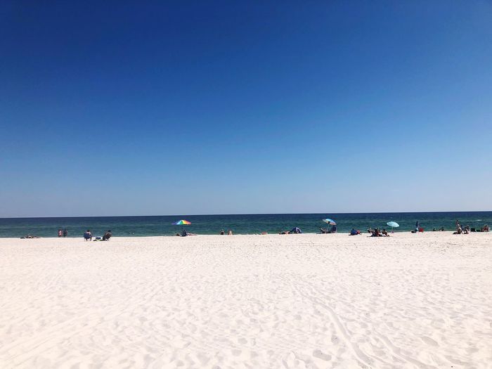 Scenic view of beach against clear blue sky