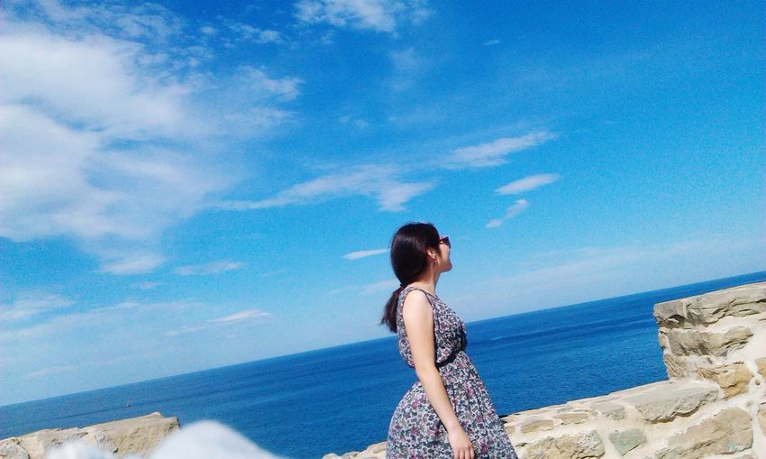 Woman standing by retaining wall against sea