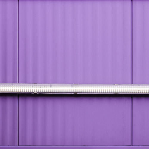 Low angle view of illuminated lighting equipment on purple wall