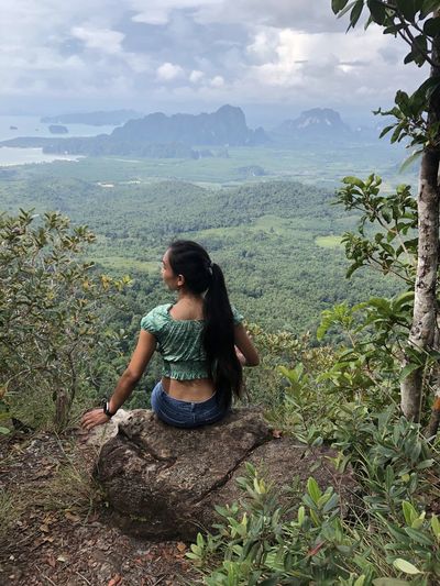 Young woman sitting on landscape against mountains