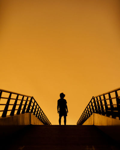 Silhouette man standing on staircase against sky during sunset