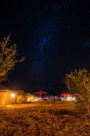 Illuminated tents on land against star field at night