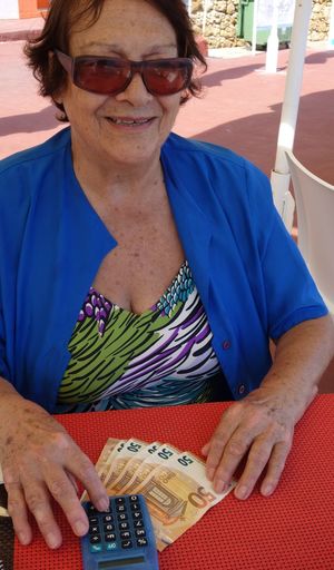 Smiling senior woman sitting with paper currency and calculator
