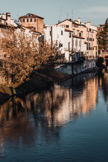 Buildings by river against sky in city