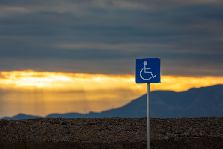 Low angle view of road sign against sky during sunset