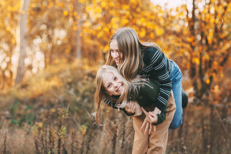 Little girls sisters laughing, having fun and playing in the fall in nature outdoors 
