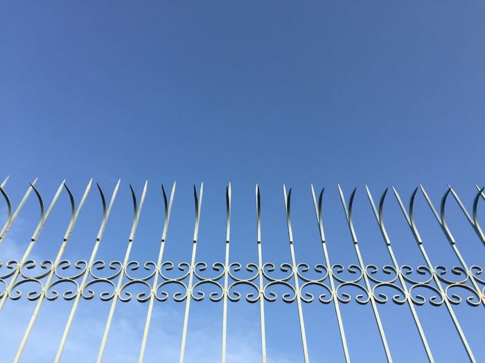 Low angle view of fence against clear blue sky