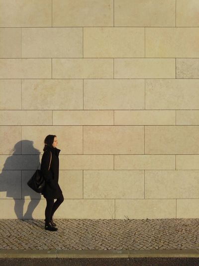 Full length of woman walking against wall