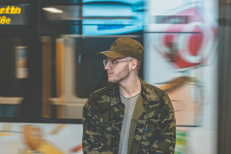 Man in camouflage jacket standing at railroad station