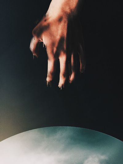 Digital composite image of hand against black background