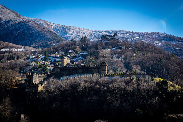 Aerial view of buildings in city against blue sky