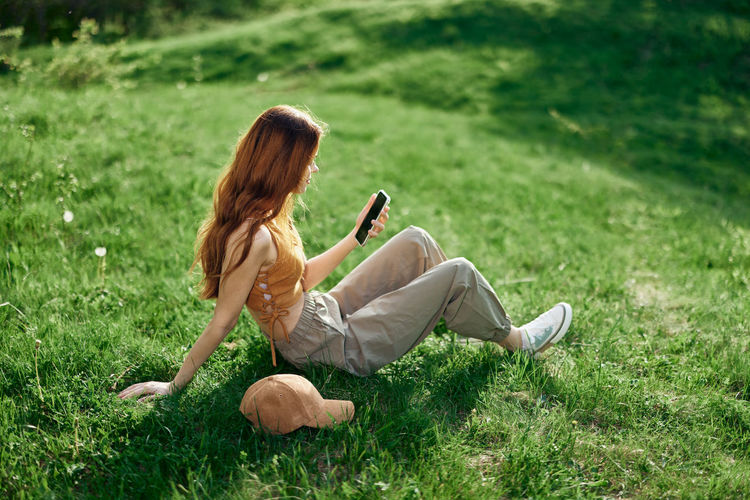 Rear view of young woman sitting on grassy field