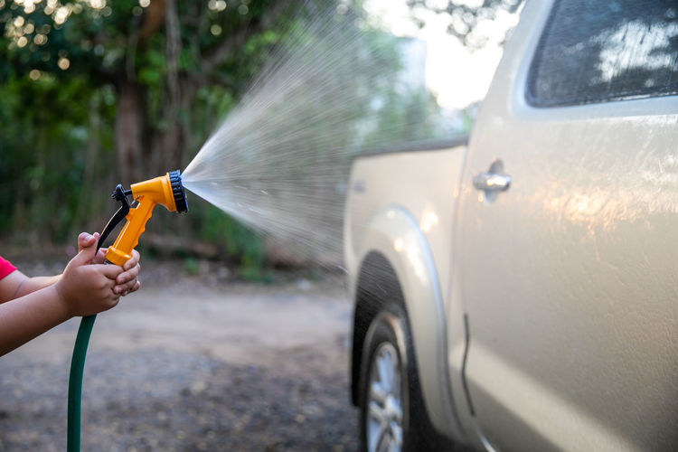Hand of man washing car with hose