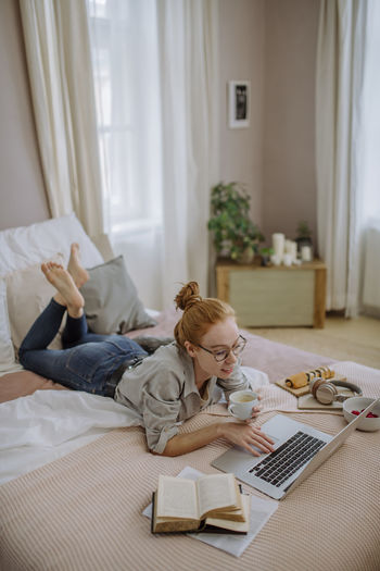 Young woman using laptop on bed at home