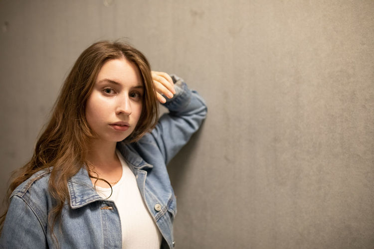 Portrait of beautiful young woman standing against wall