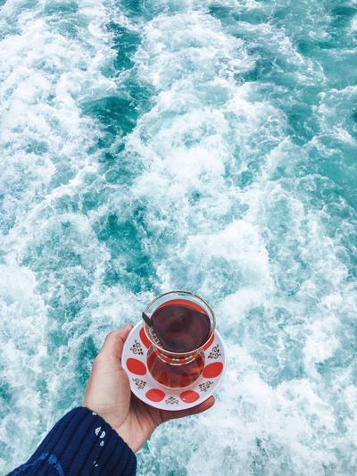 High angle view of hand holding drink at sea