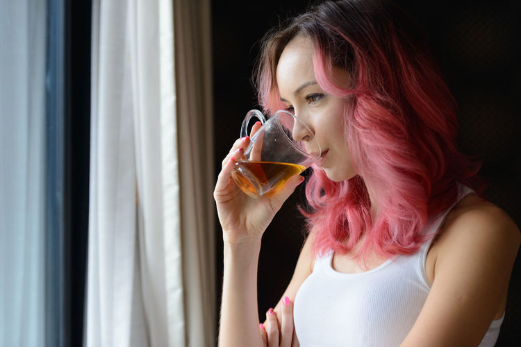 Portrait of young woman drinking from glass at home