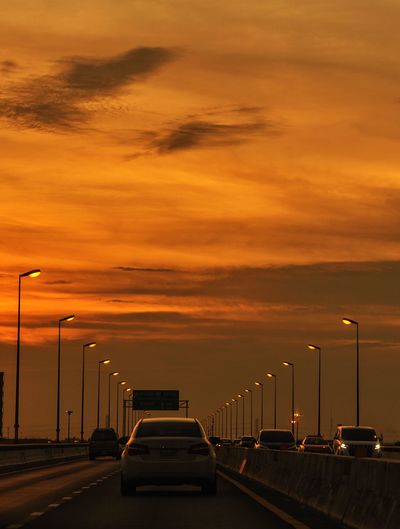Cars on street against sky during sunset