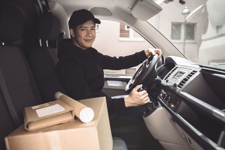 Portrait of male driver with package sitting in truck