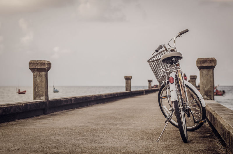 Bicycle parked on bridge over beach