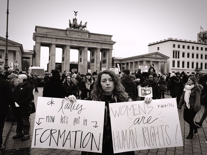 Woman holding banners with crowd against brandenburg gate