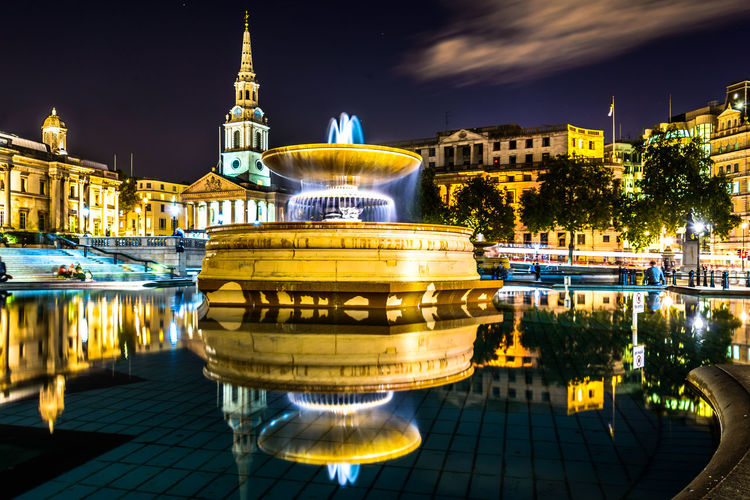 Reflection of illuminated trafalgar square in pond at night