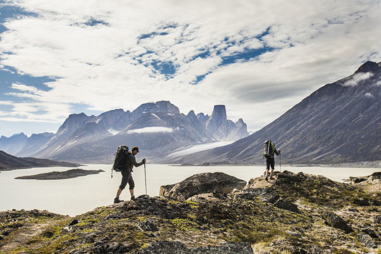 Backpackers traverse a mountain ridge in akshayak pass, baffin island.