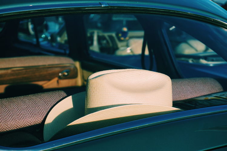 Close-up of white hat in car seen through window