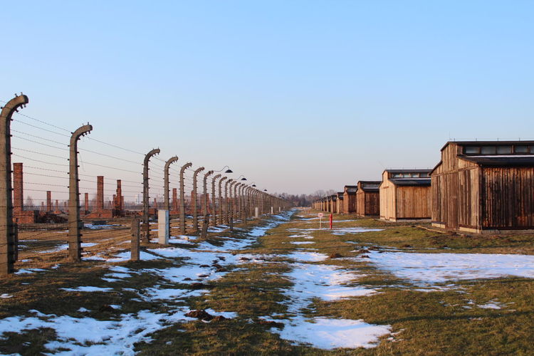 Wooden post on snow field against clear sky during winter