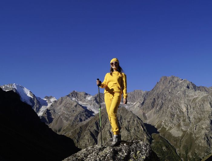 Full length of woman sanding on rock against mountains