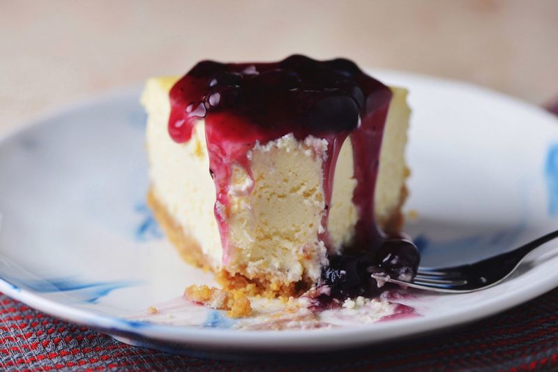 Close-up of cheesecake with blueberry sauce in plate on table
