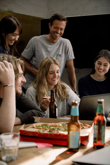 Smiling professionals eating pizza and working in office