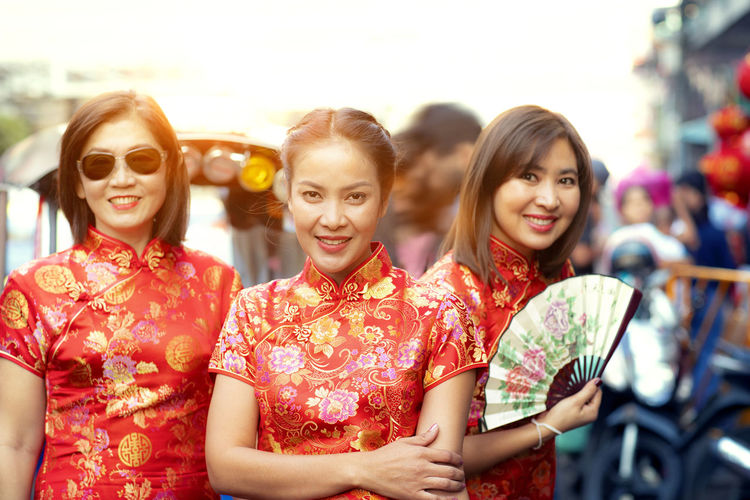 Portrait of women in traditional clothing holding hand fan standing outdoors