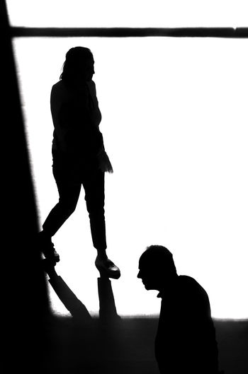 Side view of silhouette man and woman standing against clear sky