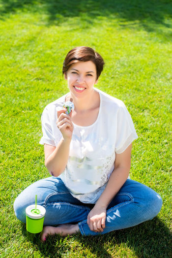 Portrait of smiling woman sitting on grassy field
