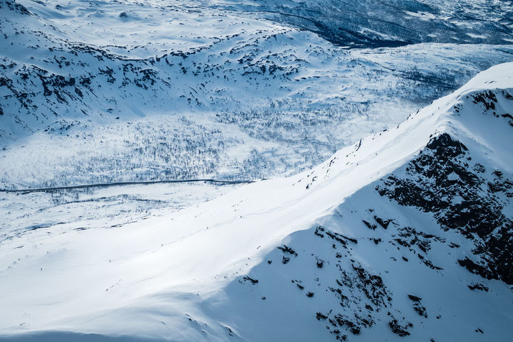 High angle view of snow covered mountain outside narvik with skiers on it