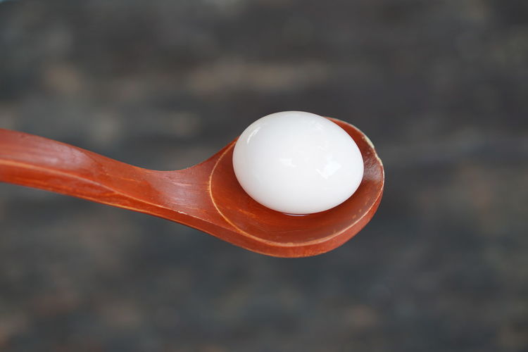 Close-up of egg in wooden spoon