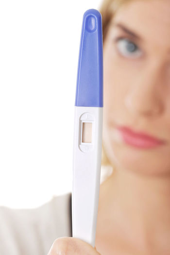 Woman holding equipment during pregnancy test against white background