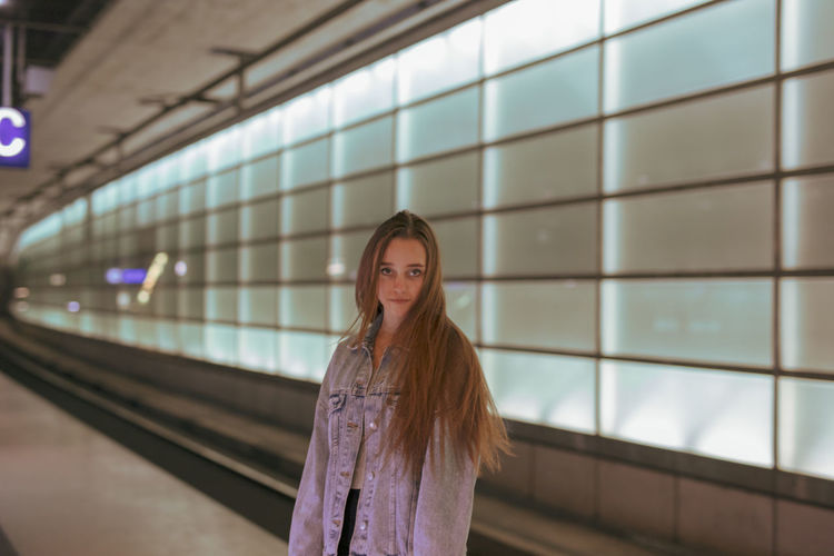 Portrait of young woman standing at railroad station platform