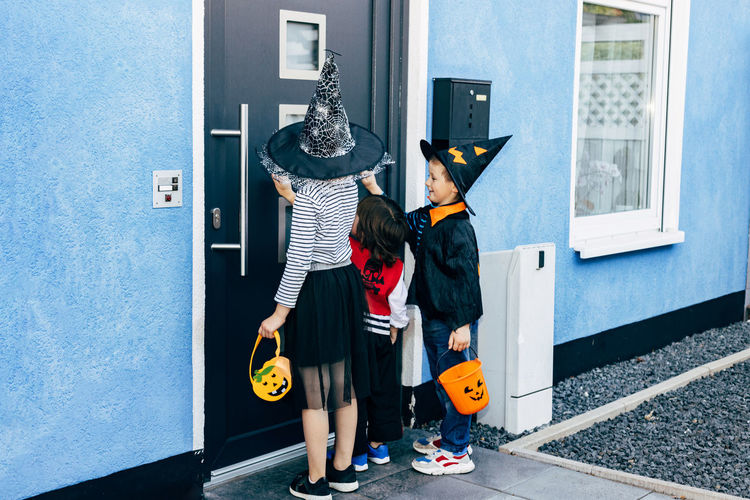  group of children in costumes dressed up for halloween go from door to door and collect sweets. 
