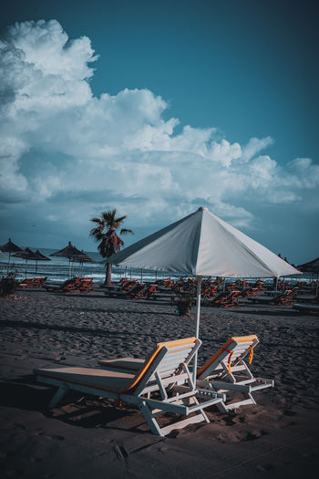 Chairs on beach against sky