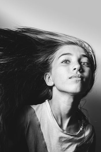 Portrait of girl tossing hair against white background