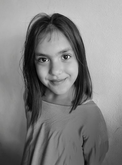 Portrait of smiling girl standing against wall