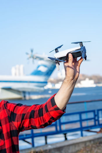 Portrait of man holding drone against blue sky