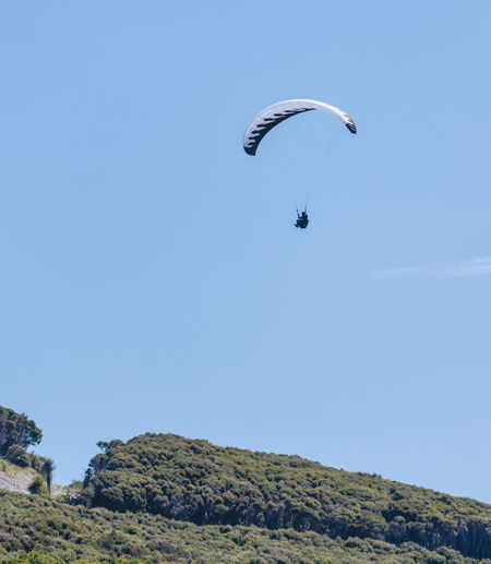 Low angle view of person paragliding against clear sky