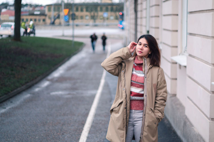 Young woman standing by building in city