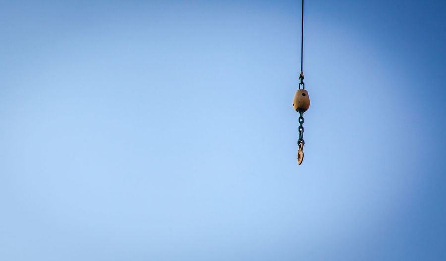 Low angle view of rope hanging against clear blue sky